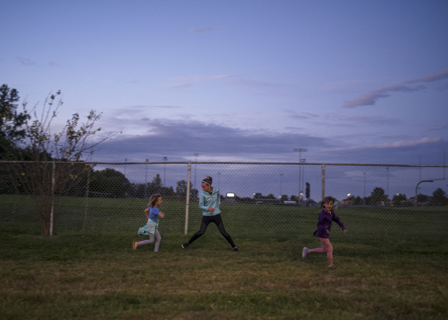 Abby, Ella, and Sophia Bowman play tag outside the game